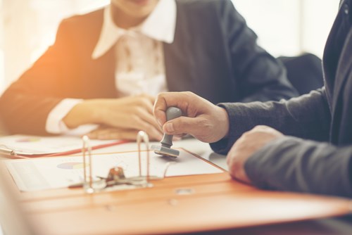 Apply for patents and certification to make your product more appealing. Business hand putting stamp on a document, close up