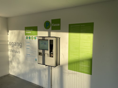 Parking payment machine attached to a wall in a parking garage with a sign providing instruction