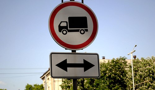 Round road sign showing a truck in a red circle and a double ended arrow showing parking is prohibited