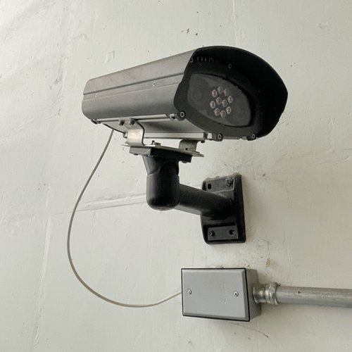 CT-45 LPR Close-up of a TagMaster NA CT-45 license plate recognition camera mounted on a wall with a metal bracket and connected conduit.