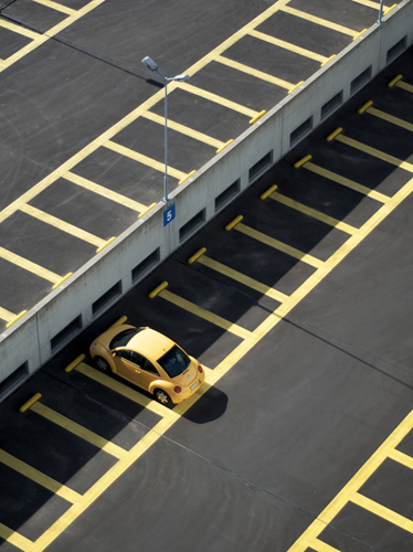 Aerial view of a parking lot with yellow lines marking bays and a yellow beetle car