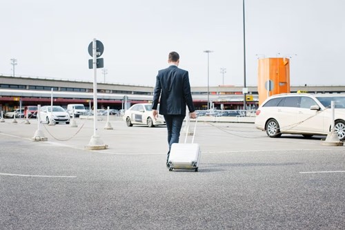 Revenue management Man pulling suitcase while walking through parking lot.