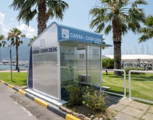 White and blue car parking kiosk with yachts, mountains, the ocean and palm trees in the background
