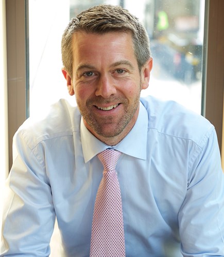 Head shot of Andy Hibbert, business man in pale blue shirt with pink tie