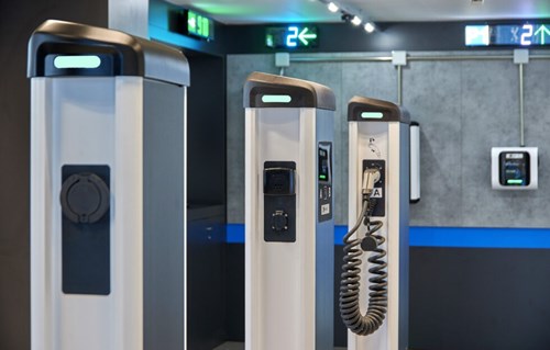 3 Ev chargers stand in a line with parking guidance LED displays in the background.