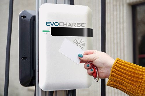 Woman's hand holds a card up to an EvoCharge EV charging unit.