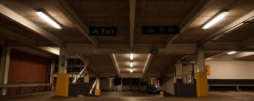 Dimly lit parking garage showing ramp between levels