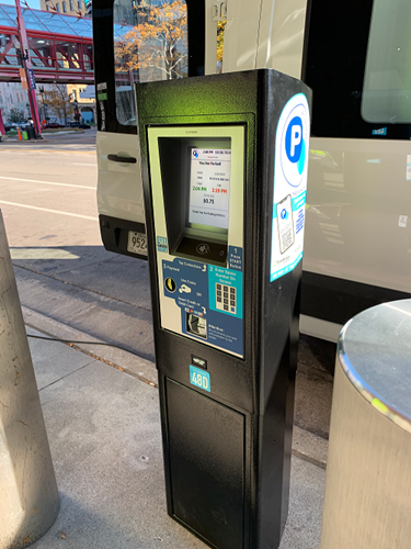 Black parking meter placed by the road, with touch screen display