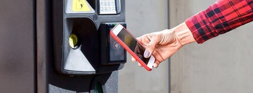 Woman holds phone up to payment station