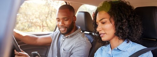 Man and woman in car look at mobile phone