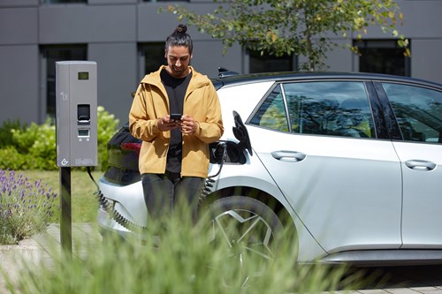 A man looking at his phone while his car charges.