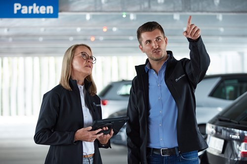 A man and a woman talking in a parking facility.