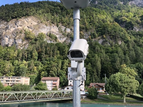 Surveillance camera in parking facility, with wooded mountain in background