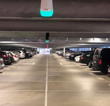Interior of a parking garage with cars parked in bays and green and red parking guidance indicators