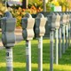 Row of old parking meters and car bonnets with grass in background