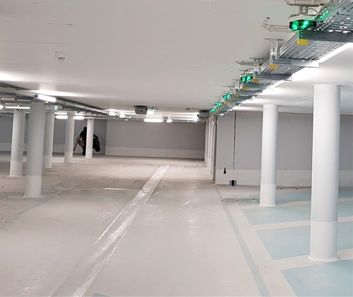 Empty, white parking garage with green occupancy parking guidance lights.