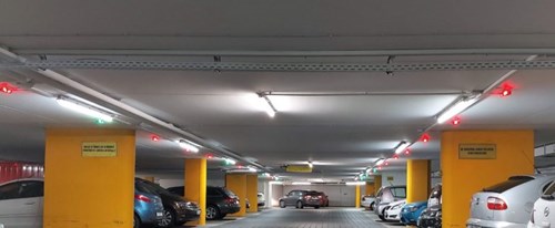 Underground parking garage with many cars and parking guidance sensors above them