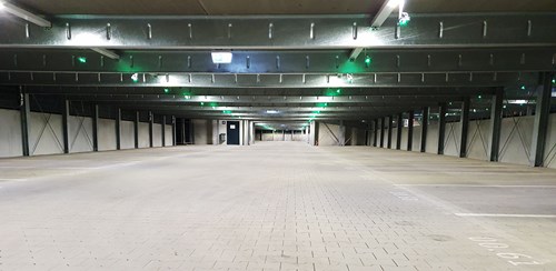 Interior of a parking garage, all bays are empty and all parking guidance ceiling lights are green.