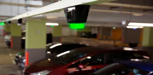 Overhead light indicators attached to parking facility roof display green LEDs
