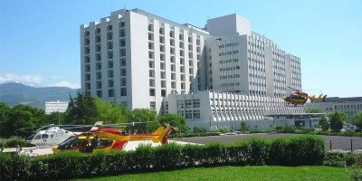 Exterior of Grenoble University Hospital, 2 parked helicopters and 1 landing 