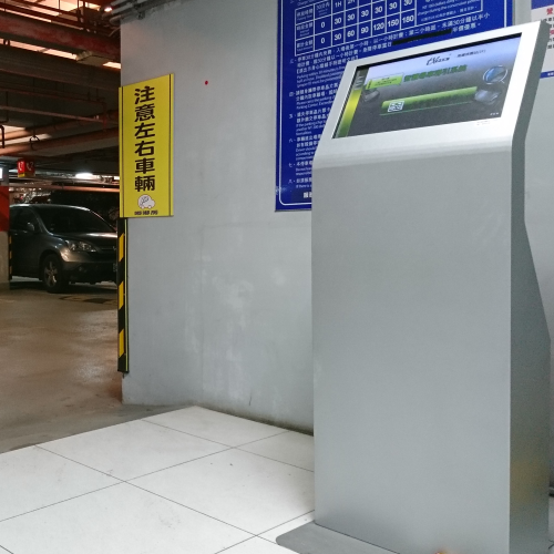 Car finder kiosk inside a parking garage, with a blue sign and parked car in the background