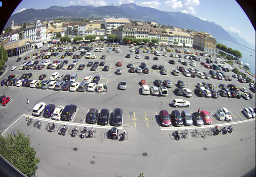 CCTV image of car parking lot in Vevey with city, lake and mountains in background