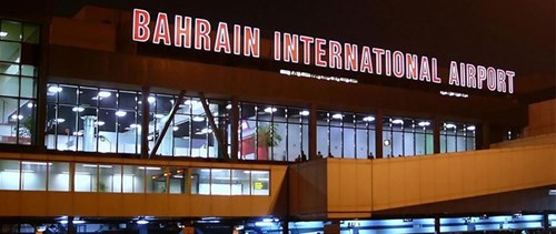 Forecourt of Bahrain International Airport at night with illuminated letters spelling the name.