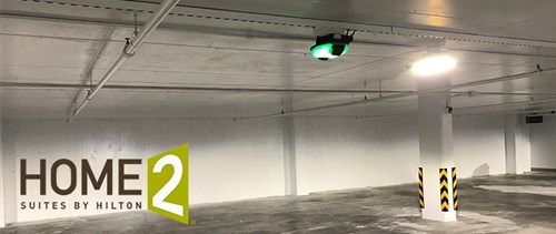 Interior of parking garage with green parking guidance light affixed to ceiling