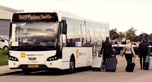 Passengers queue to enter a white airport shuttle bus