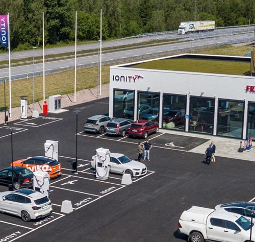 Multiple EVs charge at Ionity hub near service building.