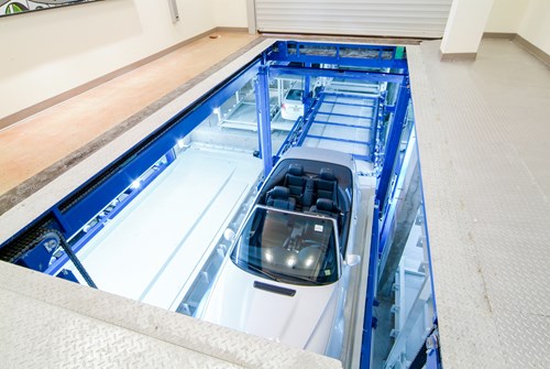 Car suspended below a garage floor using an automated system.