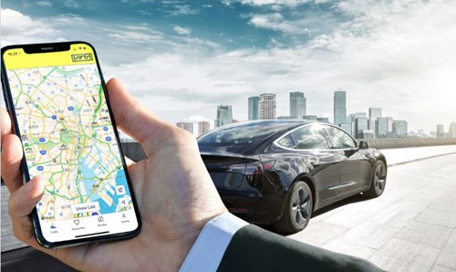 A man holds a smart phone up with a car in the background