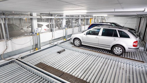 Drivers can use an RFID chip or the WÖHR Smart-Parking-App to access their parking space. Parking lift in a parking garage, two empty spaces then a silver, blue and black car