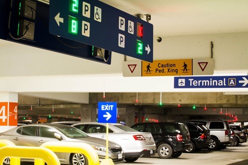 Cars in a garage with parking guidance lights and sign to Terminal A
