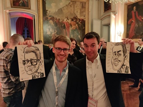 2 men hold caricatures of themselves