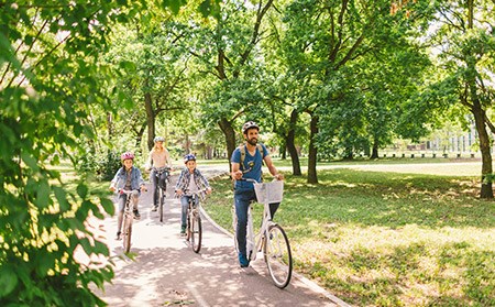 A family cycling in a park that has been kept clean using environmental enforcement