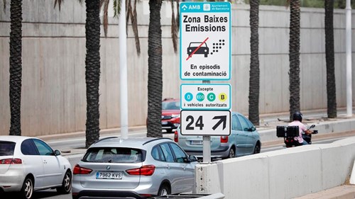 Busy two lane road in spain with signs for low emission zones