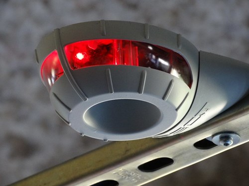 Parking guidance sensor suspended from ceiling, showing red light